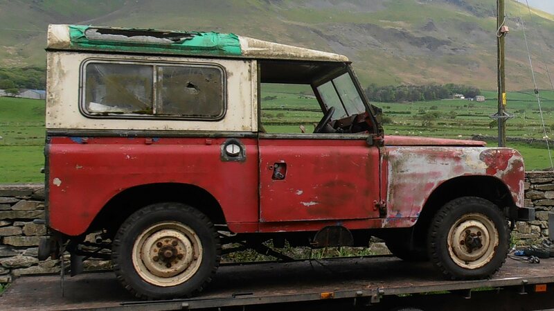Old beat up red Land Rover Series 2A on a trailer.