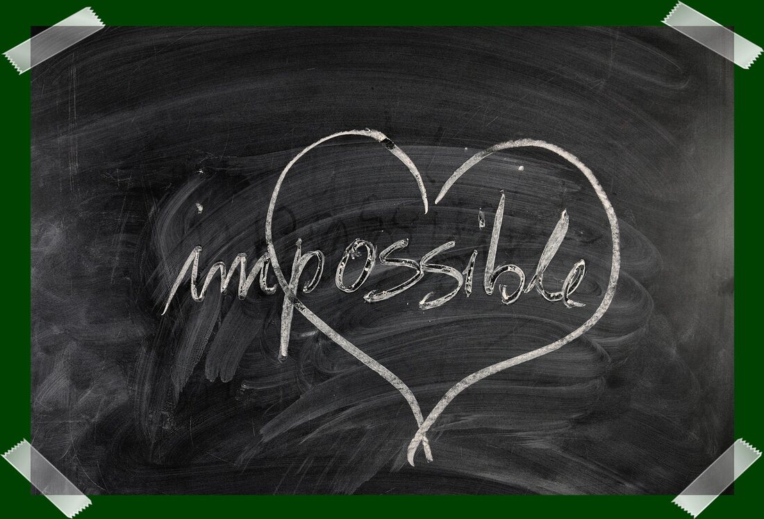 Chalkboard with white chalk writing showing the word impossible and a heart drawn around the possible part.