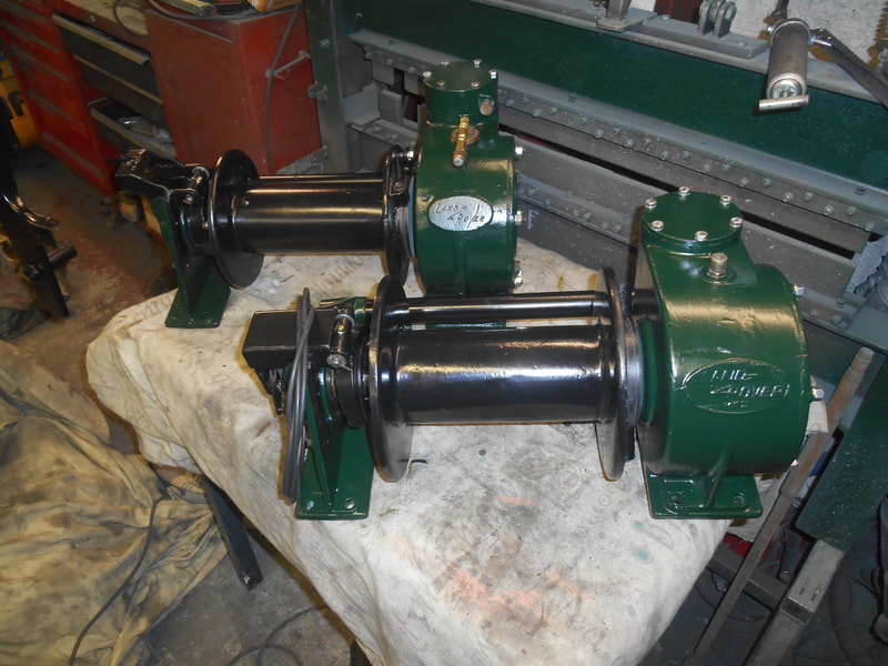 2 Land Rover Hydraulic winches after having been painted in green and black.