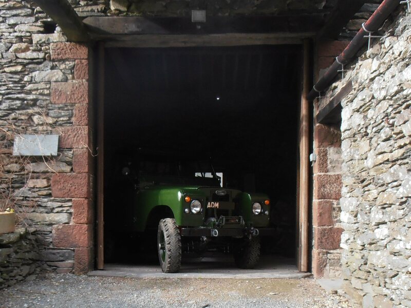 Green Land Rover Series 2a in barn door entrance, about to drive out.